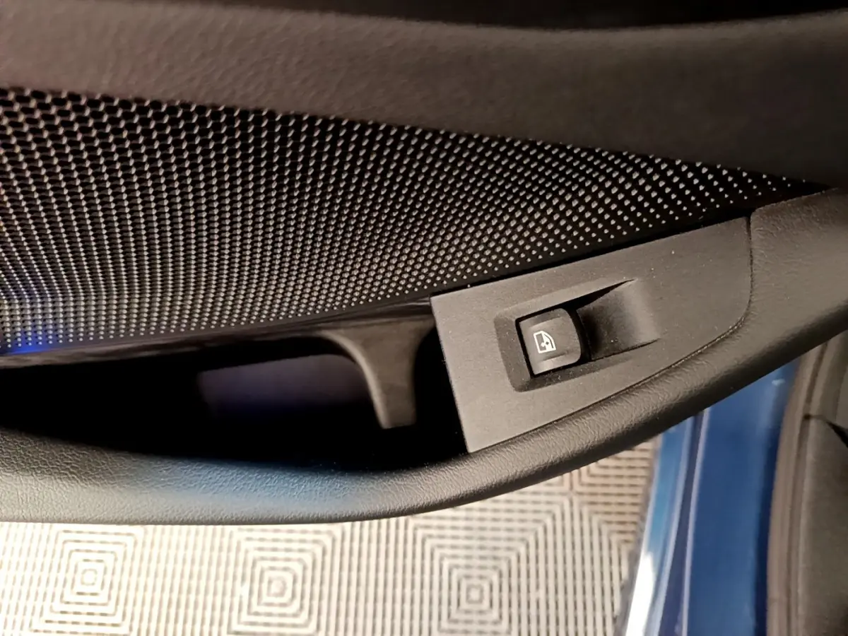 Détail de la commande de lève-vitre sur la porte côté conducteur d’une BMW Série 1 bleu 118i Edition Sport 2023.
