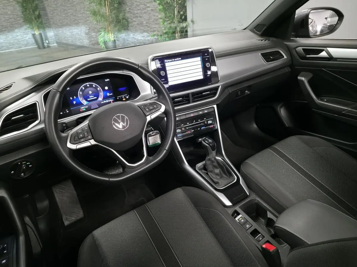 Intérieur avant du Volkswagen T-Roc gris 2024, volant cuir multifonction et écran tactile central visible.