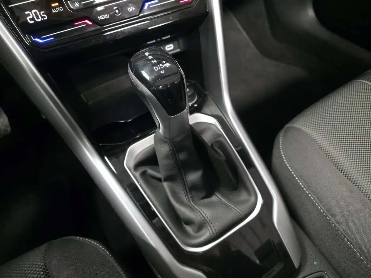 Le levier de vitesse automatique noir et argenté du Volkswagen T-Roc 2024, avec console centrale et sièges tissu gris.