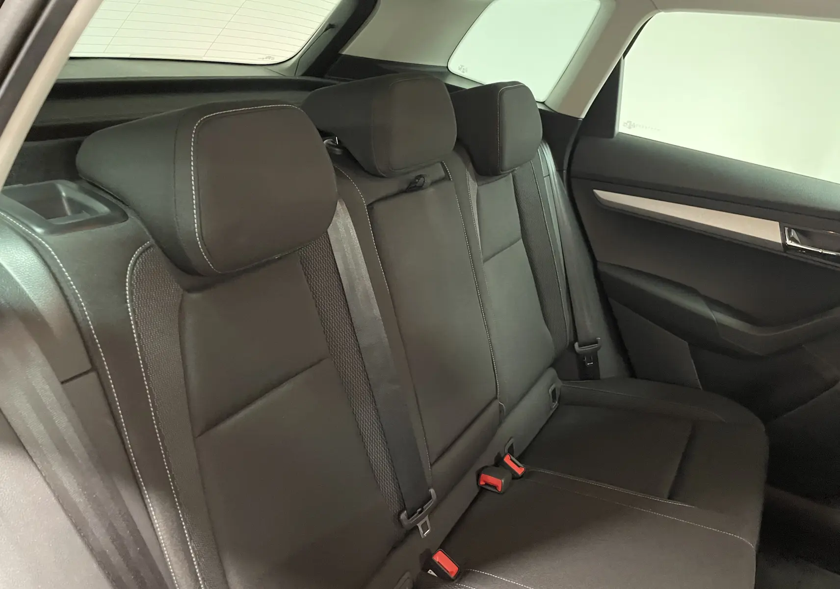 Vue du siège arrière côté droit d'un Skoda Karoq 2023 noir Magic nacré avec appuie-têtes et ceintures visibles.