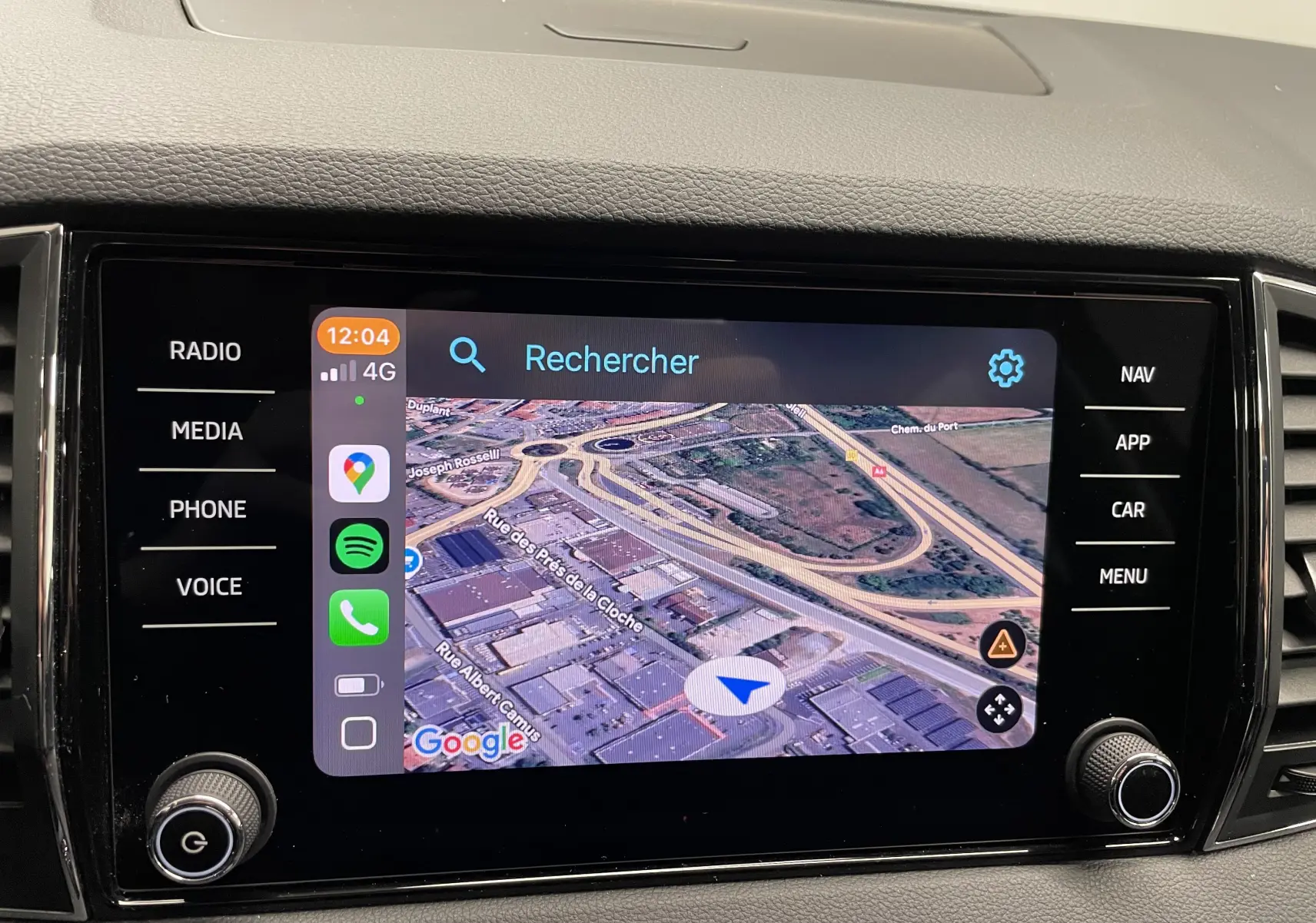 Écran central tactile du Skoda Karoq 2023 affichant la navigation GPS avec interface connectée et commandes latérales.