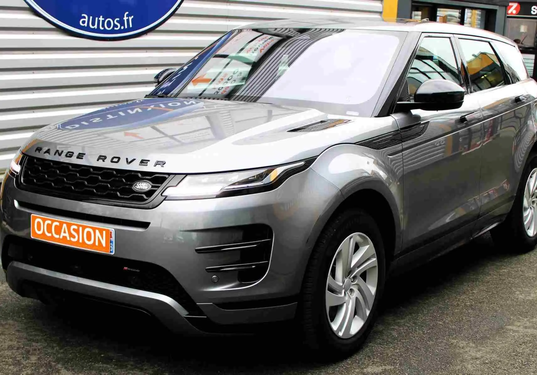 Vue 3/4 avant droit d'un Range Rover Evoque gris métal 2023 avec calandre noire et jantes argentées.