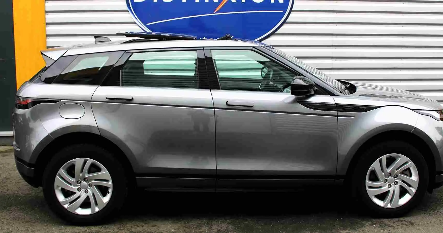 Vue latérale droite d'un Range Rover Evoque gris métal 2023, hybride rechargeable, avec jantes alliage et lignes épurées.