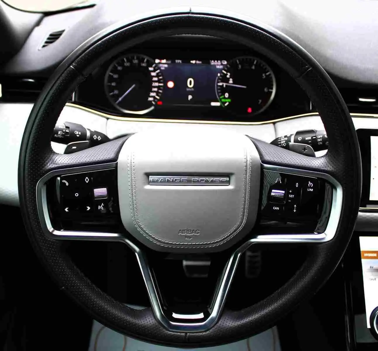 Vue rapprochée du volant cuir noir et beige du Range Rover Evoque 2023 avec commandes intégrées et tableau de bord digital.