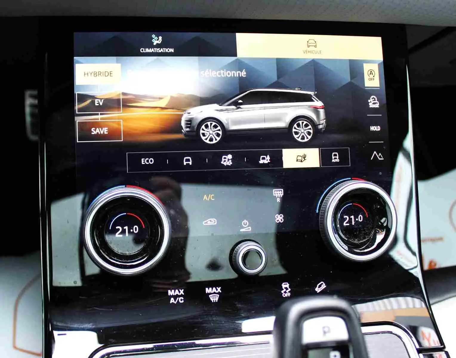 Écran tactile intérieur du Range Rover Evoque 2023 gris métal, affichant les réglages climatisation et modes hybrides.