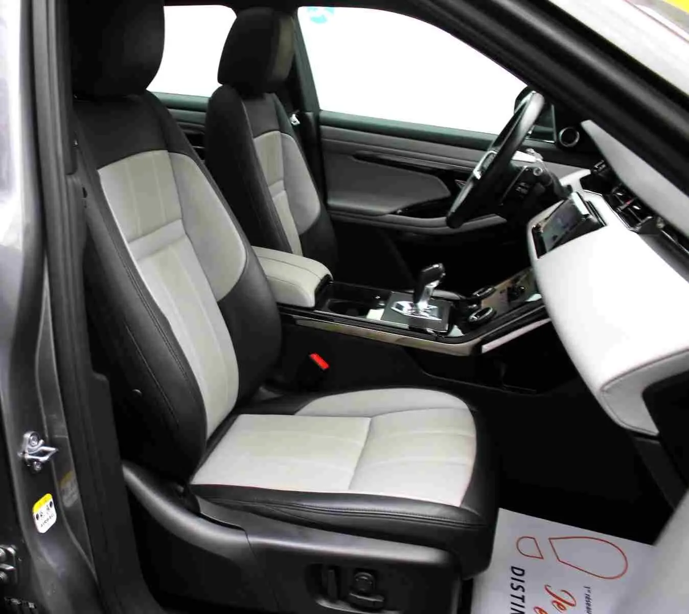 Vue intérieure côté gauche du Range Rover Evoque gris métal 2023, mettant en valeur les sièges bicolores et la console centrale moderne.