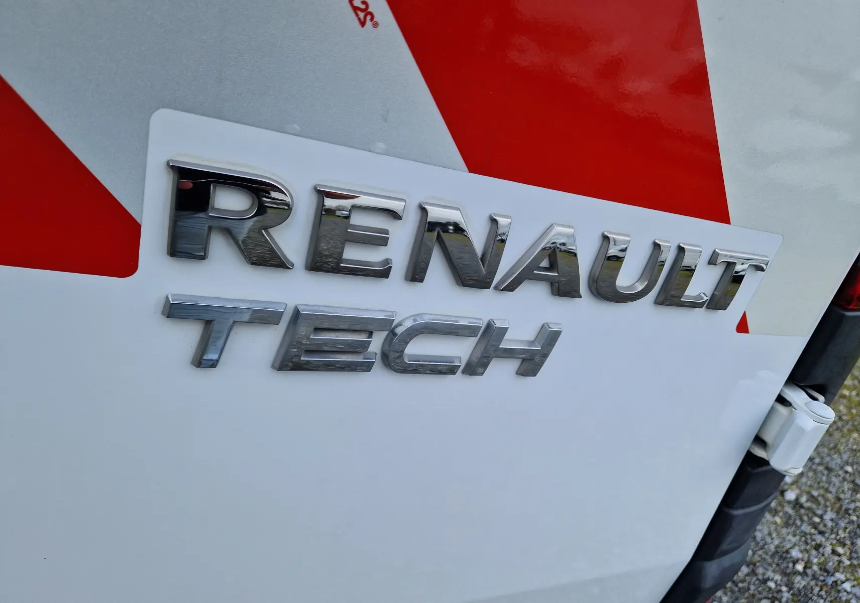 Gros plan sur l’inscription chromée Renault Tech sur la porte arrière blanche d’un Renault Kangoo utilitaire.