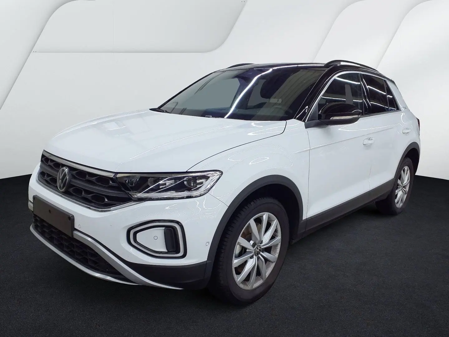 Volkswagen T-Roc blanc pure avec toit noir, vue 3/4 avant droit, jantes alliage et calandre noire distinctive.