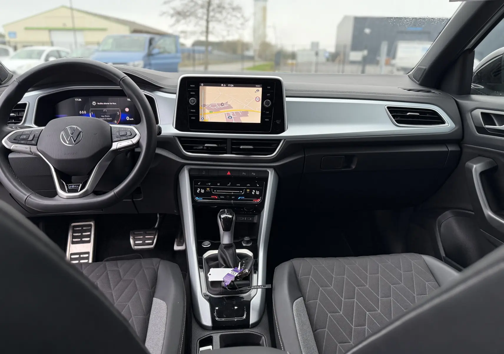 Vue intérieure avant du Volkswagen T-Roc 2025, tableau de bord moderne avec écran central et sièges tissu noir à motifs géométriques.