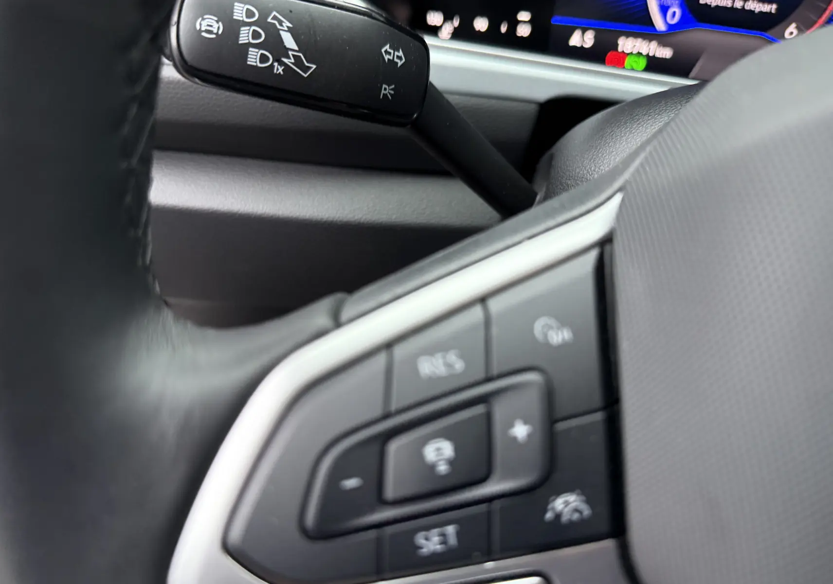 Gros plan sur la commande au volant du Volkswagen T-Roc 2.0 TDI 150ch Life Plus 2025, intérieur noir avec affichage digital.