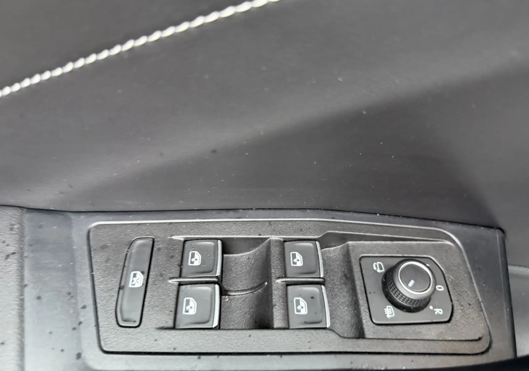 Gros plan sur les commandes des vitres électriques et rétroviseurs côté conducteur d’un Volkswagen T-Roc blanc toit noir.