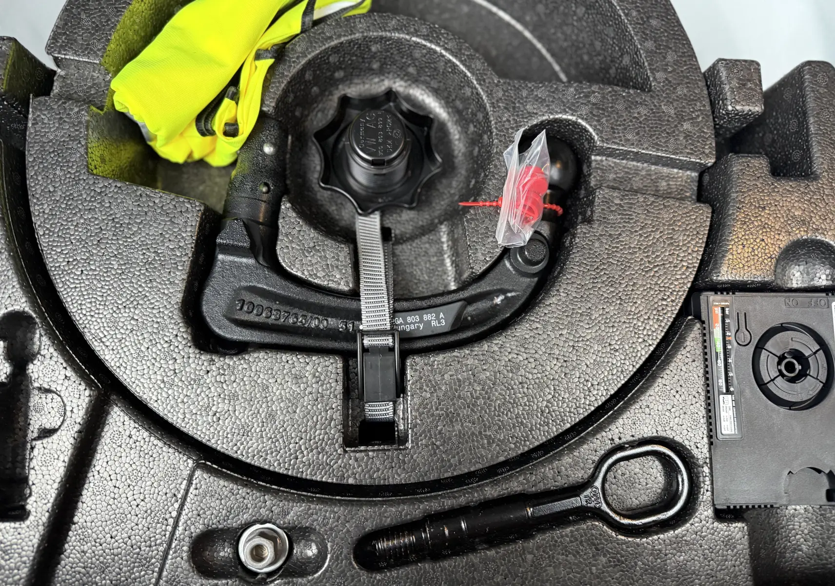 Détail du coffre du Volkswagen T-Roc 2025 avec kit de réparation pneus et gilet jaune rangé dans le compartiment noir en mousse.