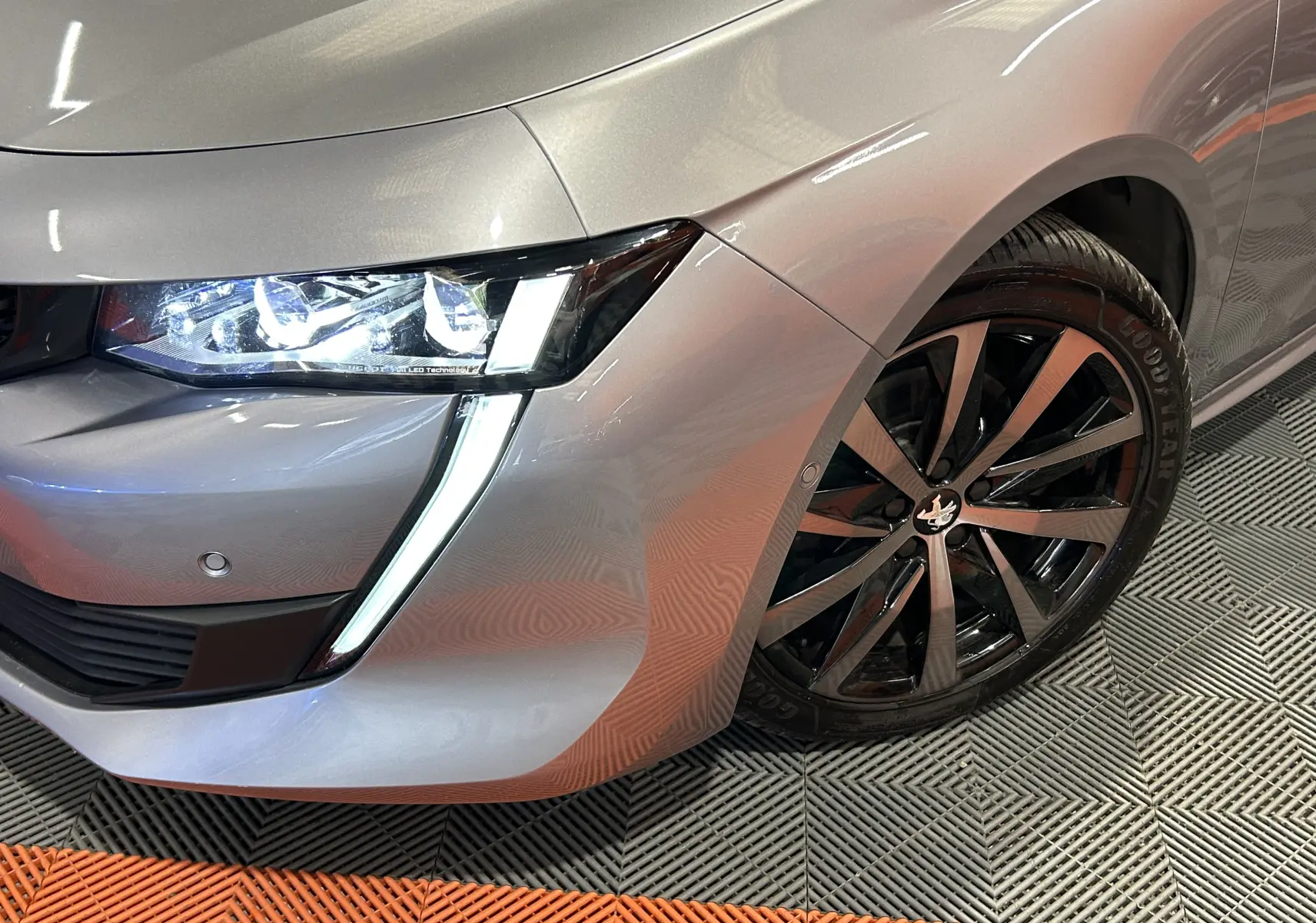 Gros plan sur l'avant droit gris Platinium d'une Peugeot 508 SW avec phare LED et jante alliage noire brillante.