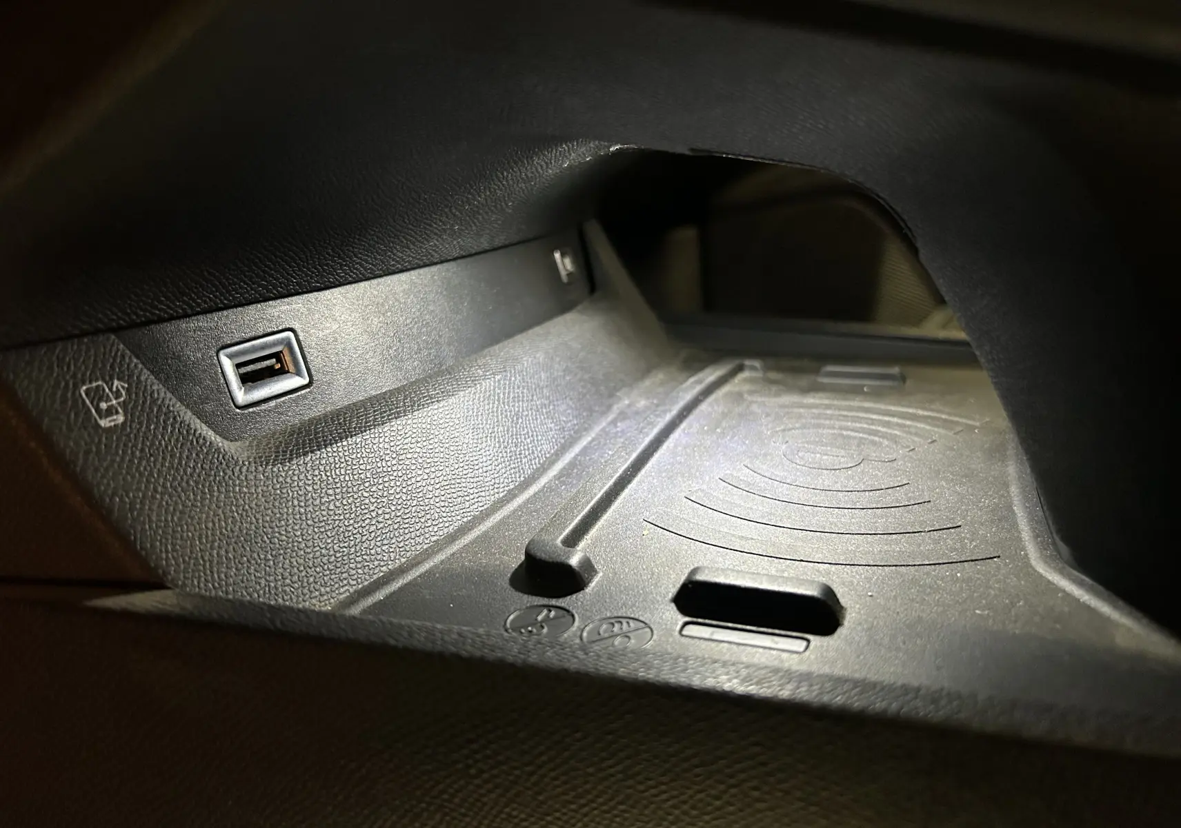 Gros plan sur le chargeur à induction et port USB dans l'habitacle noir du Peugeot 508 SW Gris Platinium.