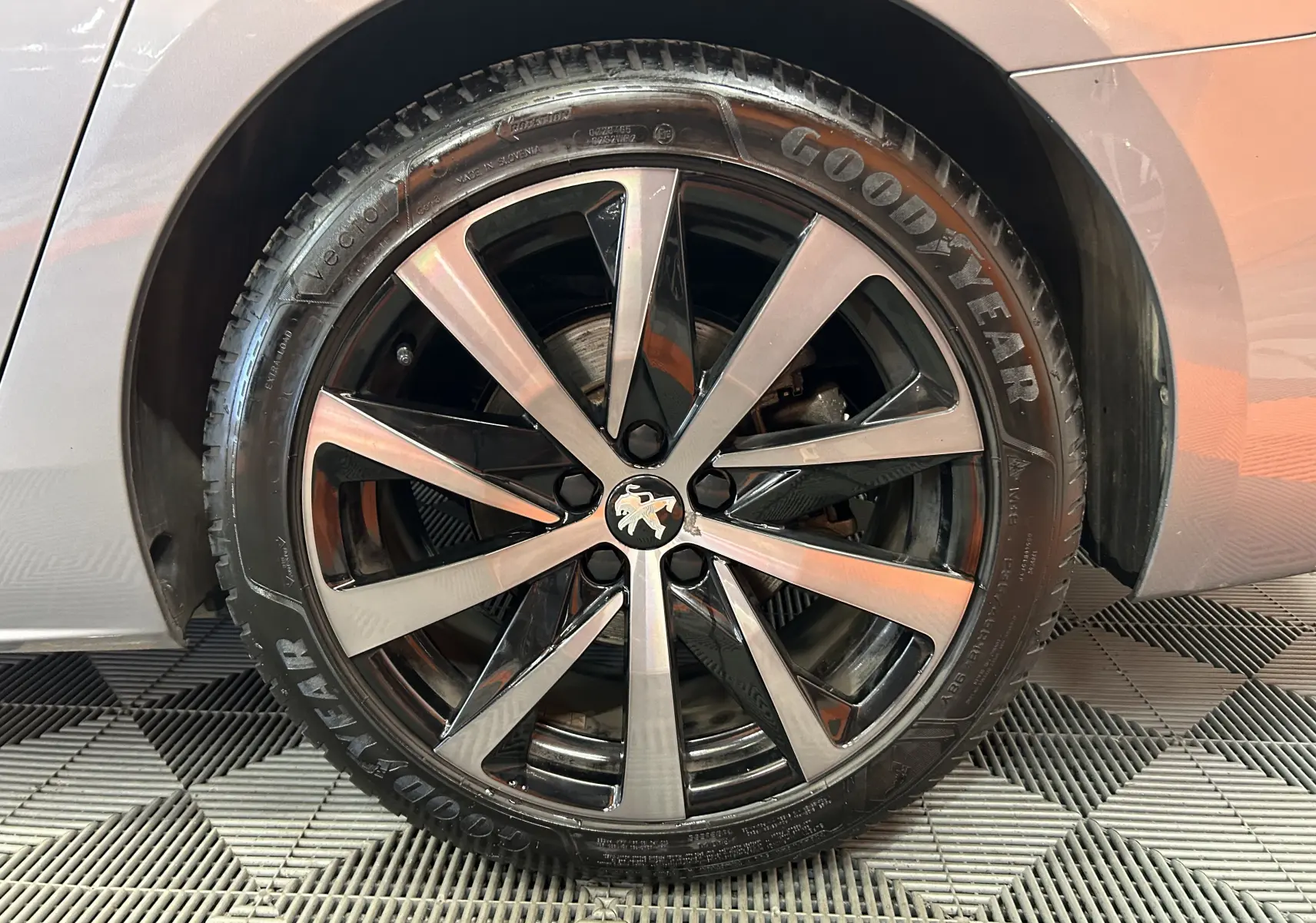 Gros plan sur la roue avant droite d'une Peugeot 508 SW gris Platinium avec jante alliage bicolore et pneu Goodyear.