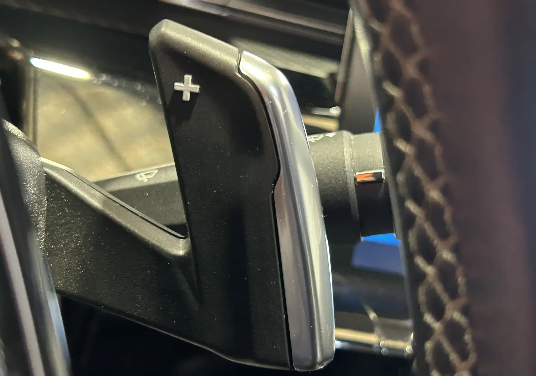 Gros plan sur la palette de changement de vitesse + côté droit du volant en cuir perforé d’une Peugeot 508 SW gris Platinium.