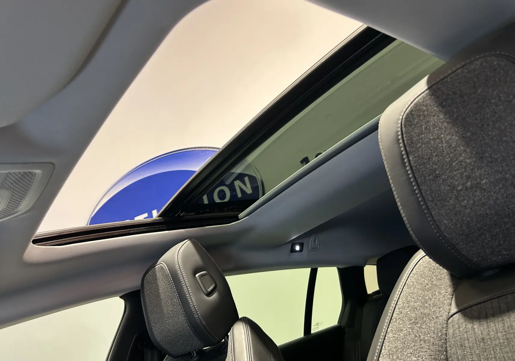 Vue intérieure du toit ouvrant panoramique et des sièges avant gris du Peugeot 508 SW Gris Platinium.
