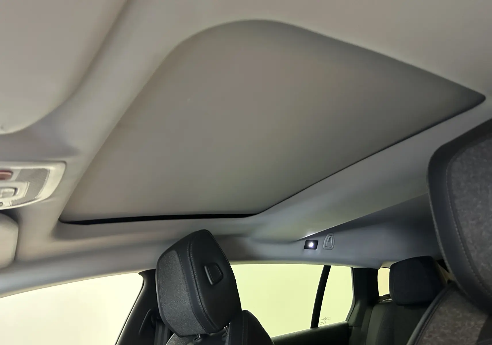 Vue intérieure du toit ouvrant fermé et des sièges avant en tissu noir du Peugeot 508 SW Gris Platinium.