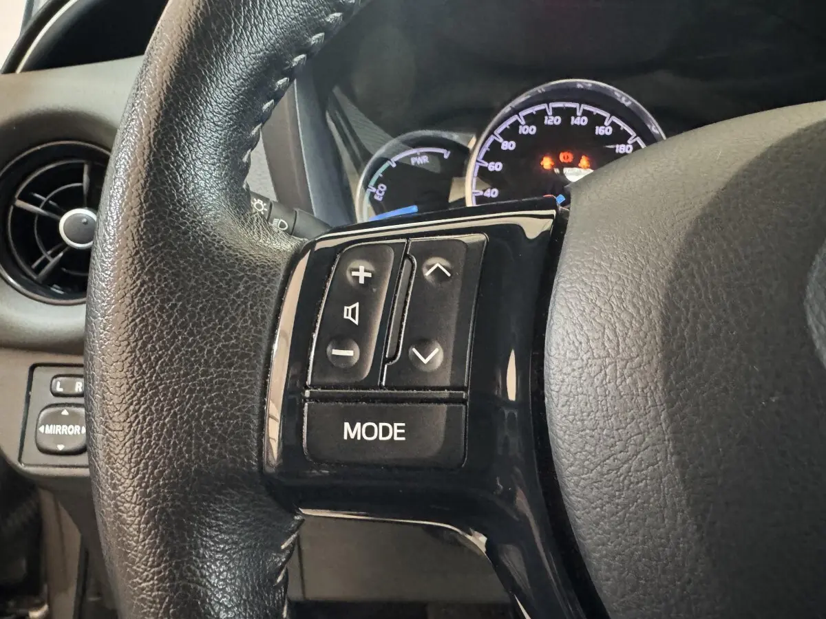 Gros plan sur le volant cuir noir de la Toyota Yaris 2019, avec commandes audio intégrées côté gauche.