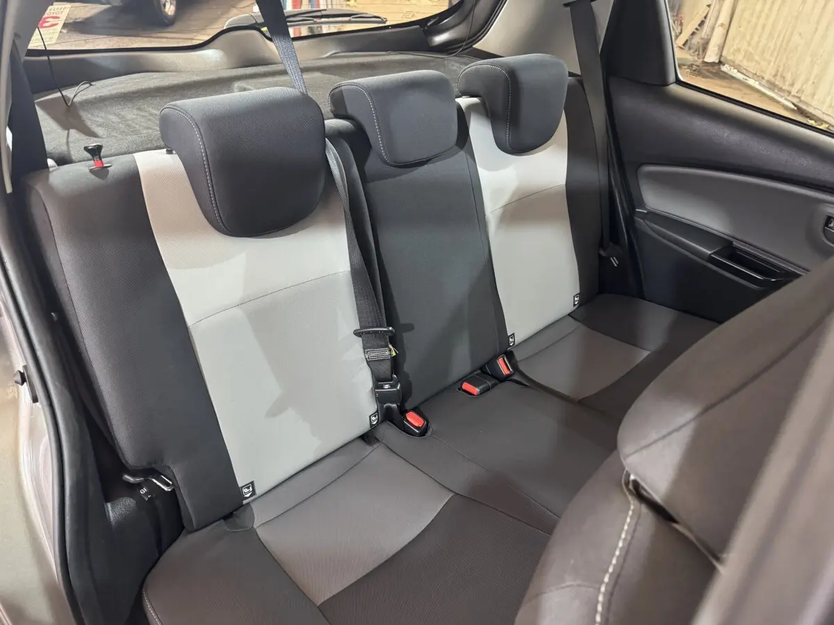 Vue intérieure de la banquette arrière bicolore gris clair et foncé de la Toyota Yaris 2019, avec appuie-têtes et ceinture de sécurité.