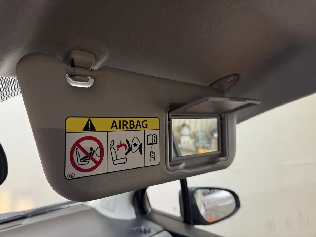 Détail du pare-soleil côté conducteur avec miroir et avertissement airbag dans l’habitacle d’une Toyota Yaris gris foncé.