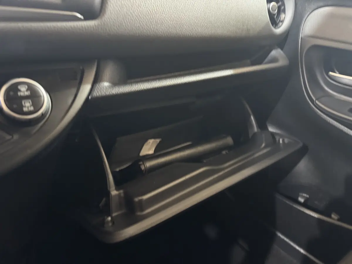 Vue rapprochée de la boîte à gants ouverte côté passager dans une Toyota Yaris 2019 gris foncé, intérieur noir.