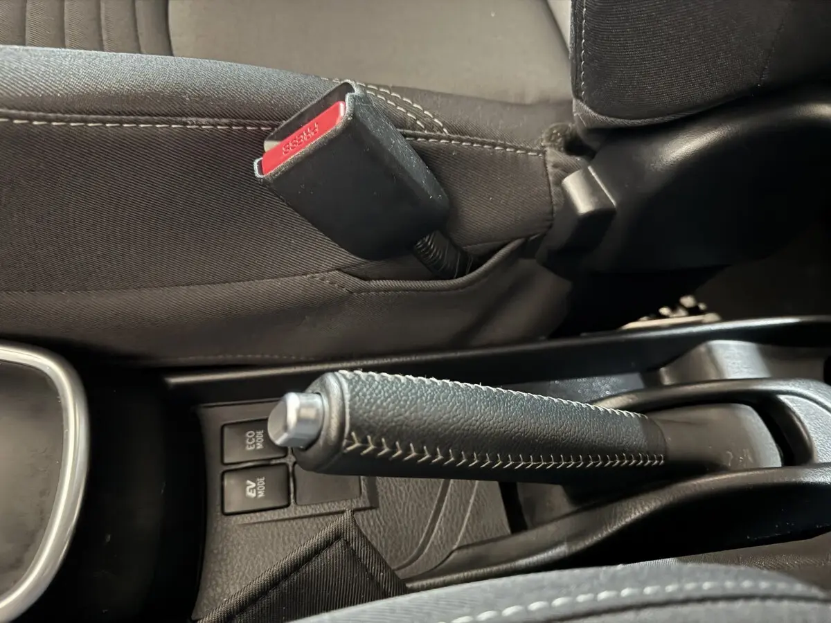 Gros plan sur le frein à main en cuir noir et la ceinture de sécurité grise à l'intérieur de la Toyota Yaris hybride 2019.
