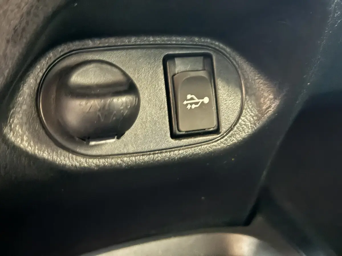 Détail intérieur du bouton d'ouverture du capot sur une Toyota Yaris 1.5 VVT-I Hybrid 2019, plastique noir.