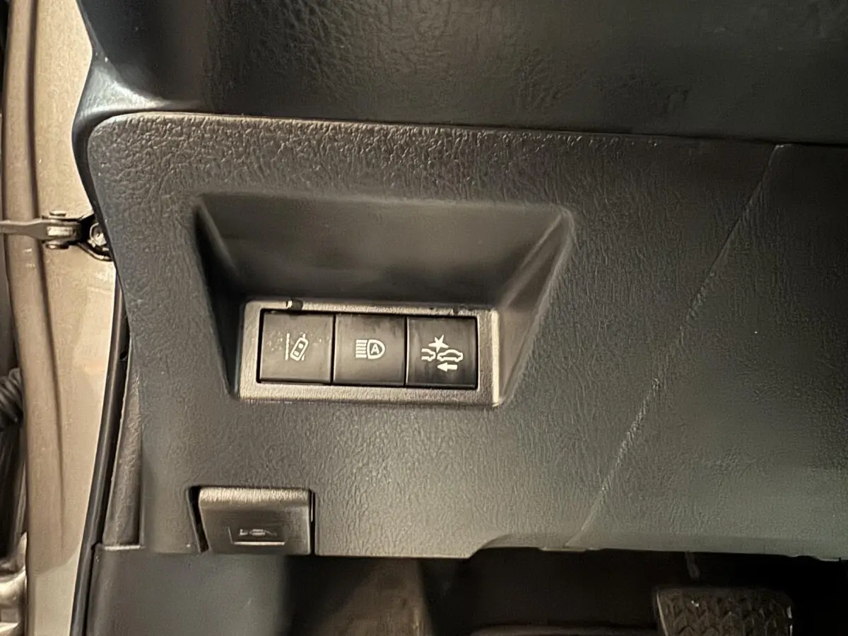 Gros plan sur les commandes de sécurité côté gauche du tableau de bord d'une Toyota Yaris gris foncé 2019.