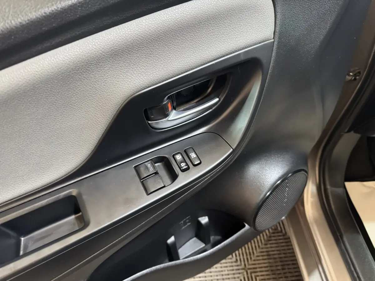 Gros plan sur la porte avant gauche de la Toyota Yaris gris foncé, montrant la poignée, les commandes de vitres et haut-parleur.