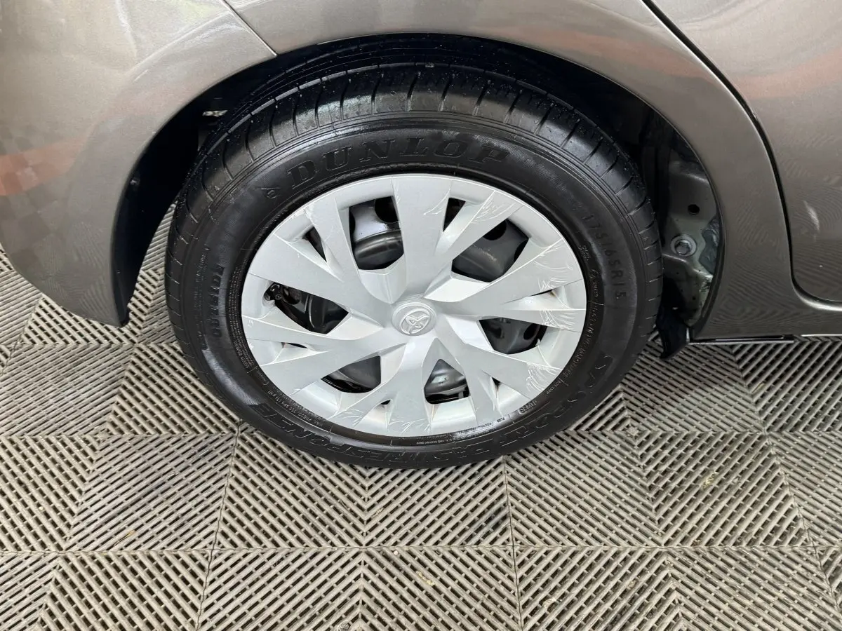 Gros plan sur la roue arrière droite grise foncée d'une Toyota Yaris 1.5 VVT-I Hybrid avec jante en plastique et pneu Dunlop.