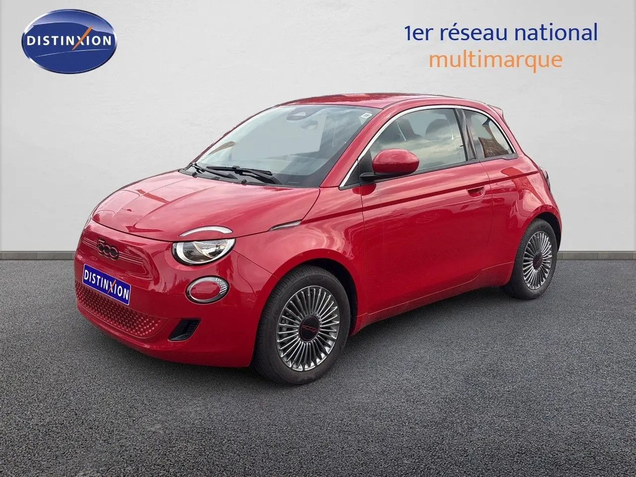 Vue 3/4 avant droite d'une FIAT 500e rouge électrique avec jantes classiques et phares ronds distinctifs.