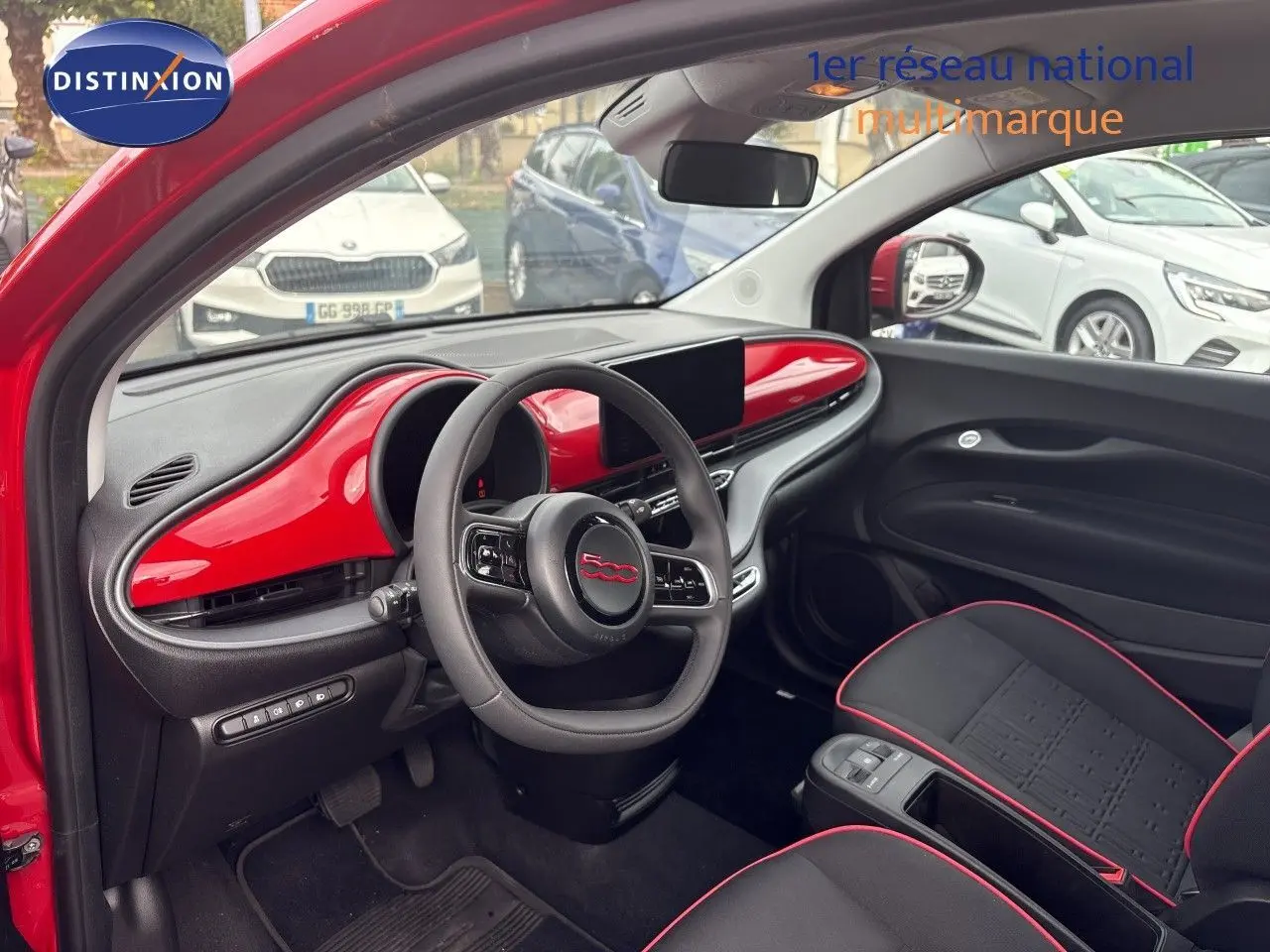 Vue intérieure côté conducteur de la FIAT 500e rouge 2024, tableau de bord et volant avec insert rouge brillant.