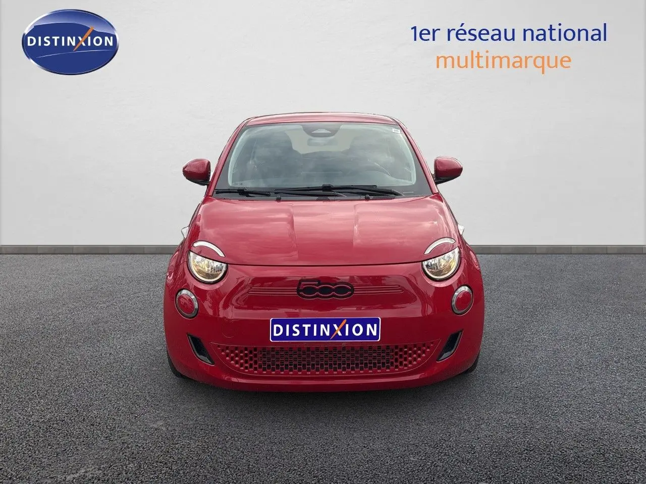 Vue frontale d'une FIAT 500e rouge électrique 2024 avec logo 500 noir et phares ronds allumés.