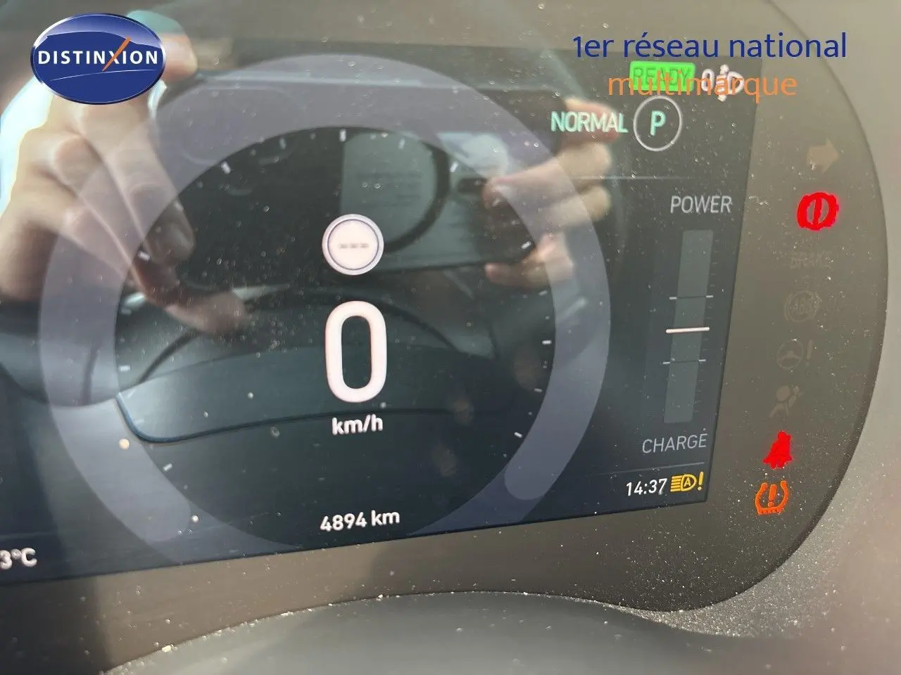 Tableau de bord numérique de la FIAT 500e rouge, affichant 0 km/h et 4894 km au compteur, avec voyants allumés.