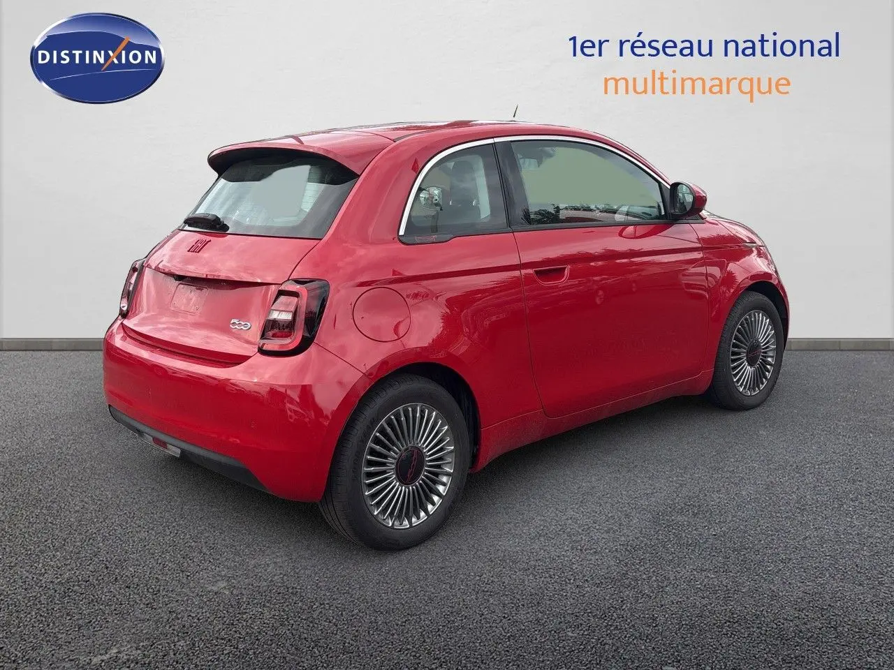 Vue 3/4 arrière droite d'une FIAT 500e rouge électrique 2024 avec jantes classiques et feux arrière foncés.