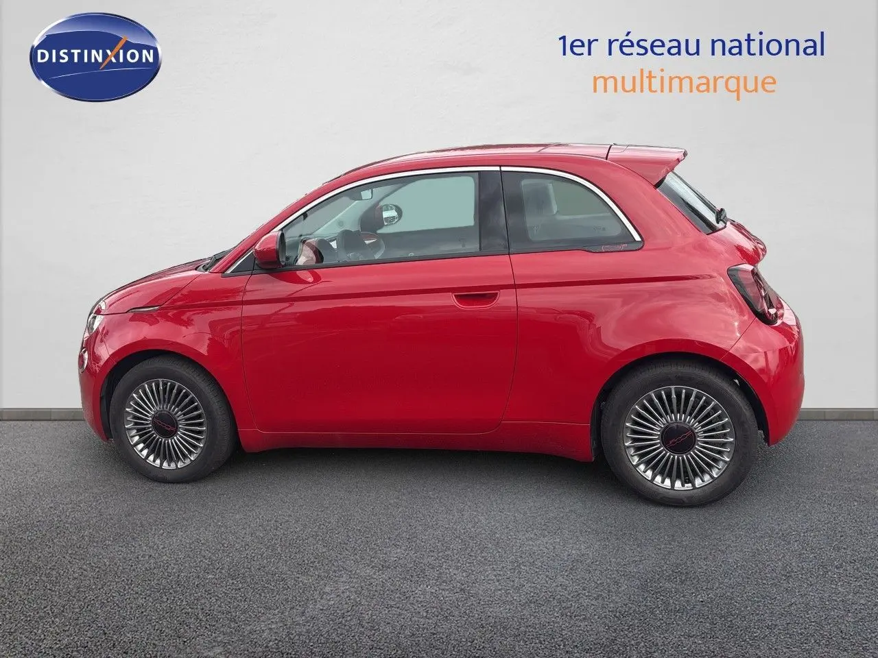 Profil droit d'une FIAT 500e rouge électrique 2024 avec jantes classiques et toit arrondi compact.
