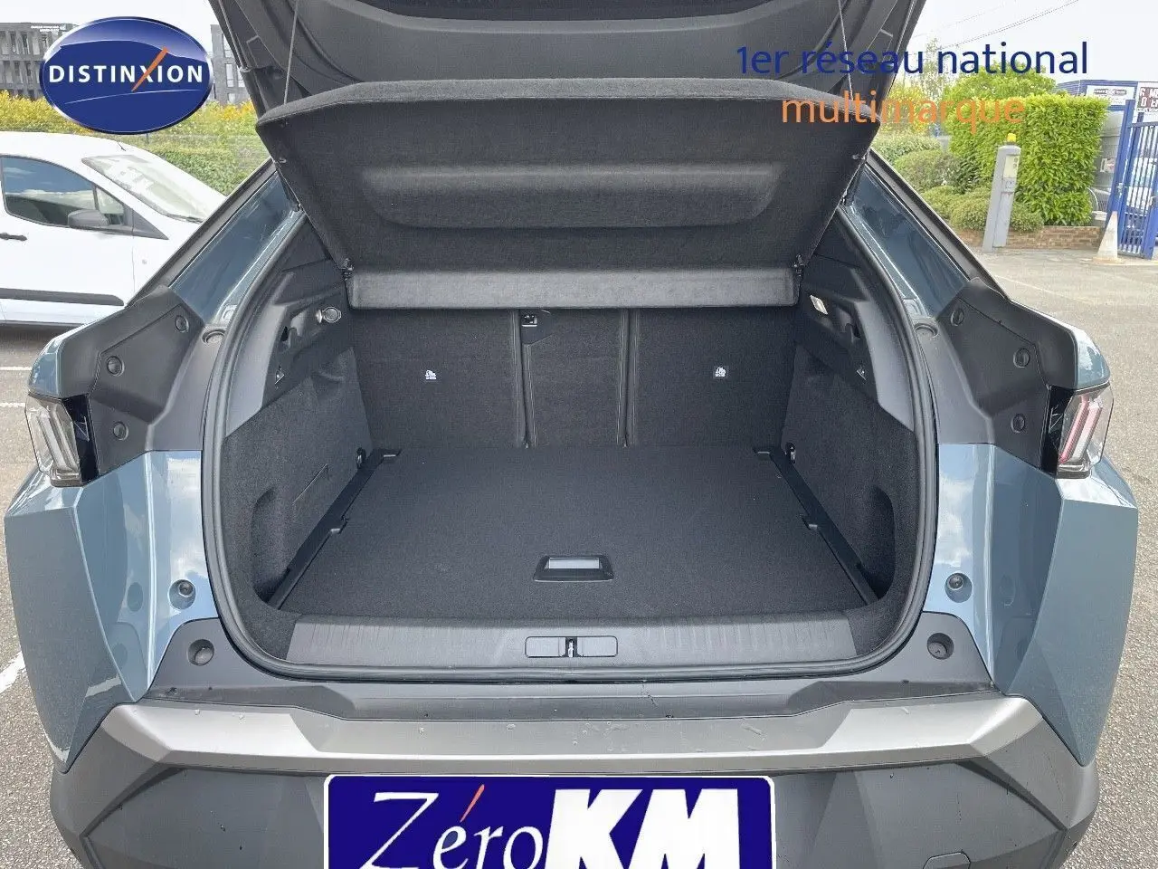 Coffre ouvert du Peugeot 3008 Hybrid 136ch Allure bleu Ingara Metal vu de l'arrière, montrant un espace de chargement spacieux.