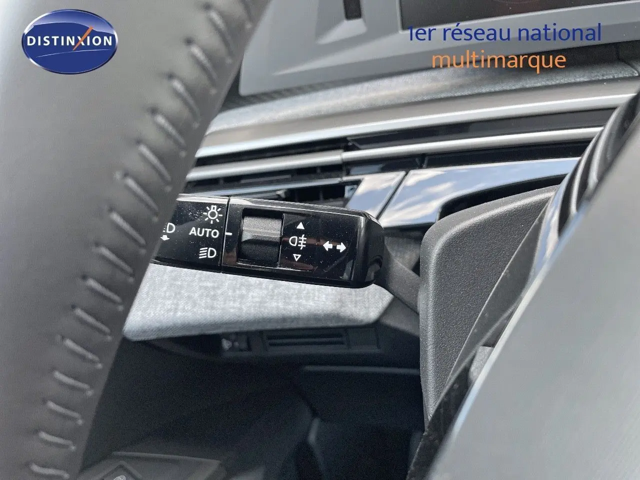 Vue rapprochée du commodo d'éclairage à gauche du volant dans l'habitacle du Peugeot 3008 Hybrid bleu Ingaro Metal 2025.