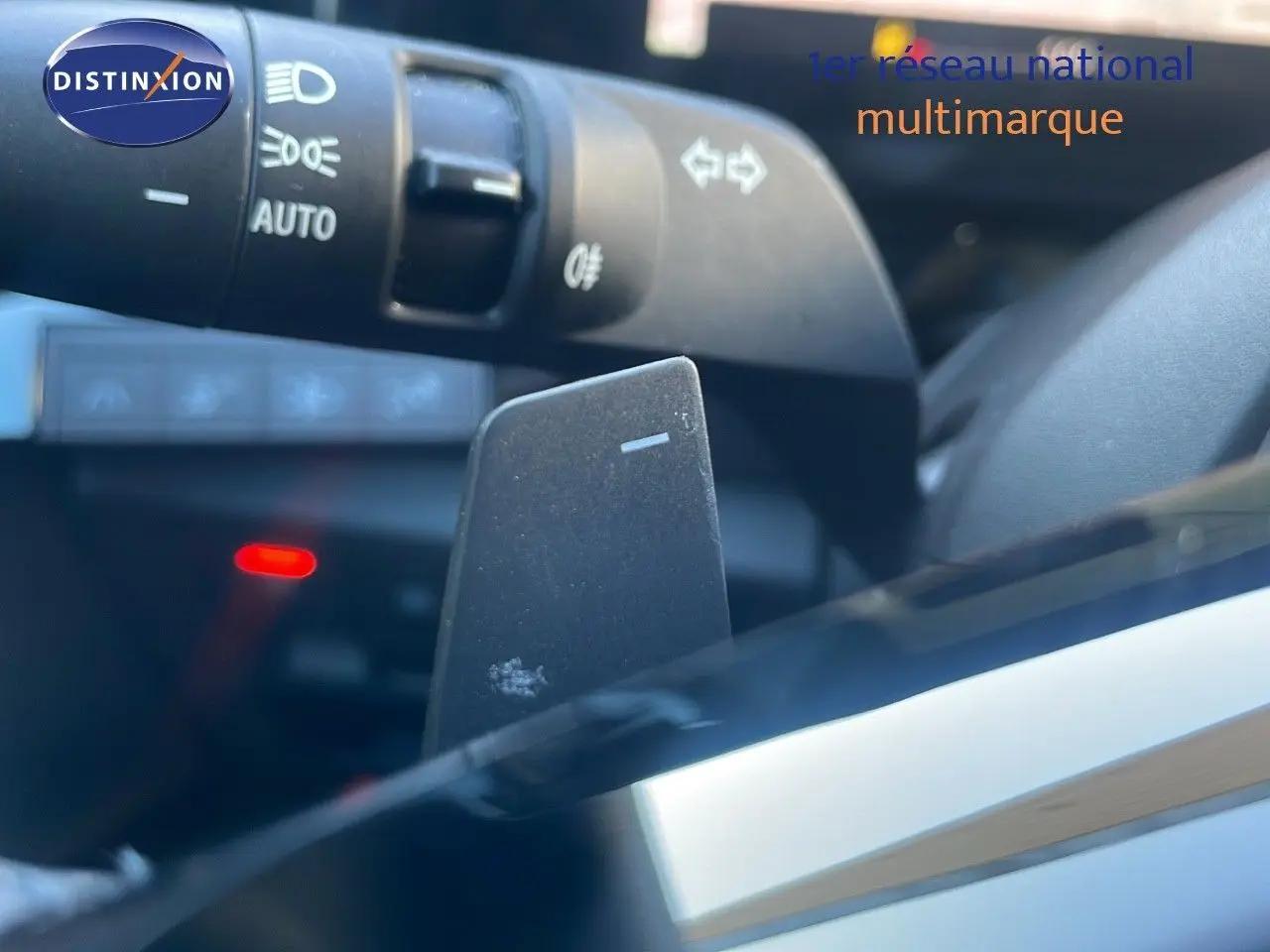 Gros plan sur la palette de changement de vitesses et la commande des phares dans l'habitacle du Renault Austral blanc glacier 2023.