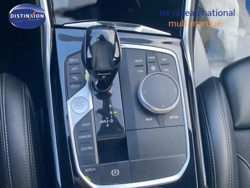 Gros plan sur la console centrale noire de la BMW Série 3 G20, avec levier de vitesses et commandes de mode de conduite.