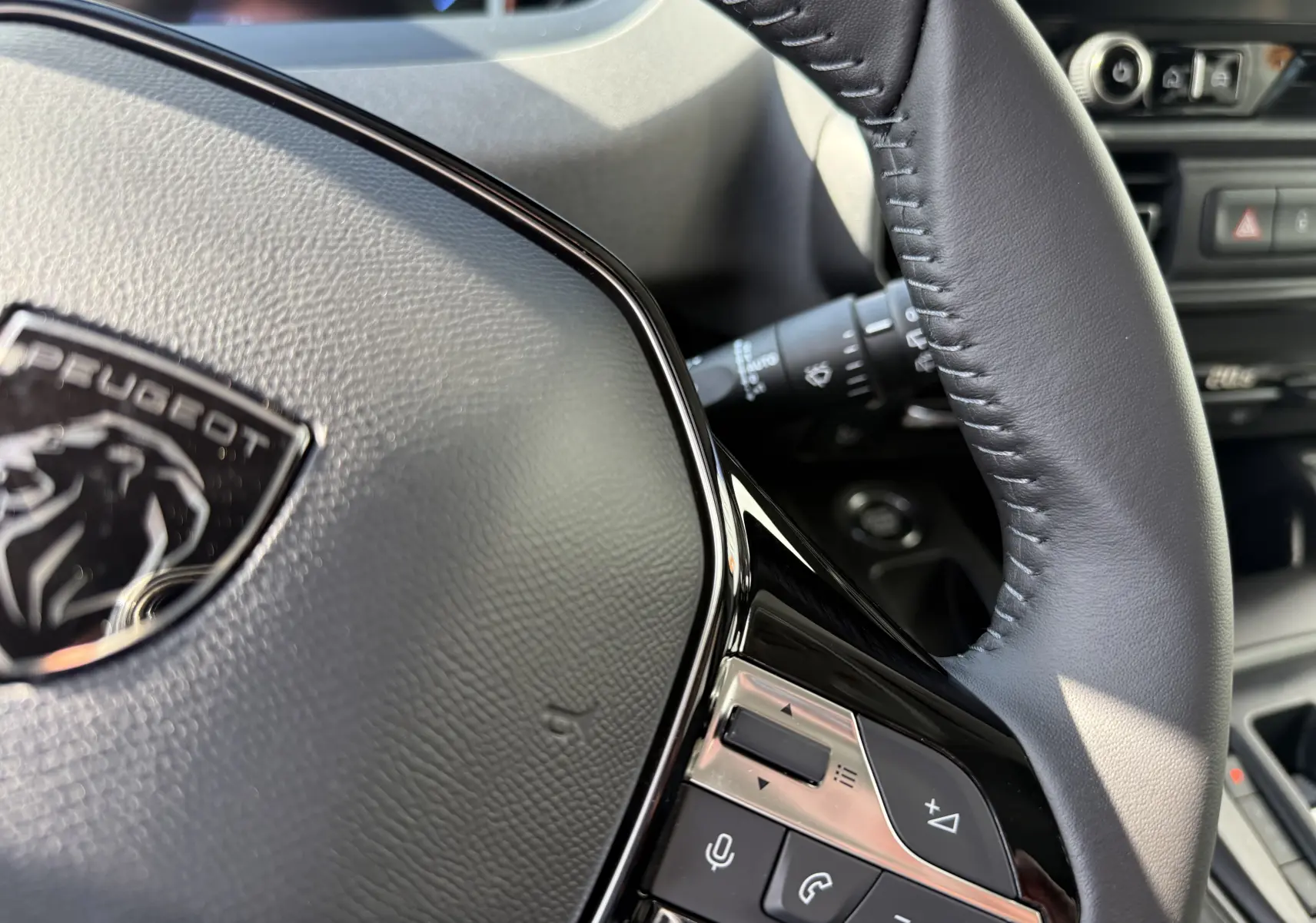 Gros plan sur le volant cuir noir du Peugeot Rifter Allure 2026, avec commandes audio et téléphone intégrées.