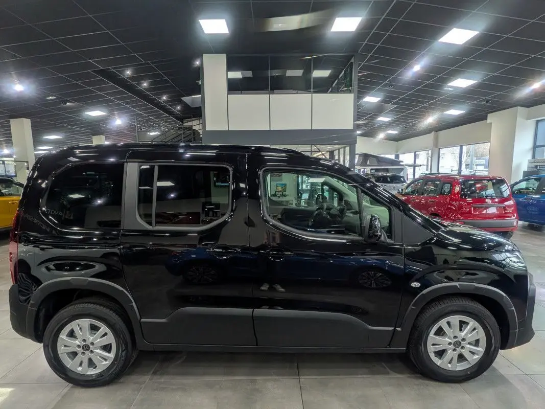 Vue de profil côté gauche d’un Peugeot Rifter Allure 2026 noir Perla Nera dans un showroom lumineux.