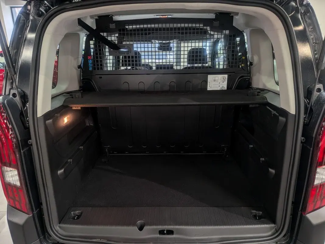 Coffre ouvert du Peugeot Rifter noir Perla Nera, vue arrière montrant la grille de séparation et le plancher de chargement.