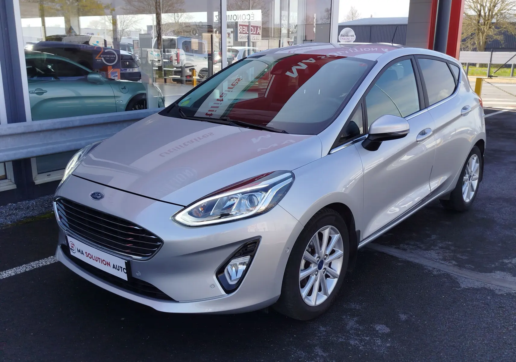 Vue 3/4 avant droite d'une Ford Fiesta gris lunaire 2019 avec jantes alliage et calandre noire brillante.