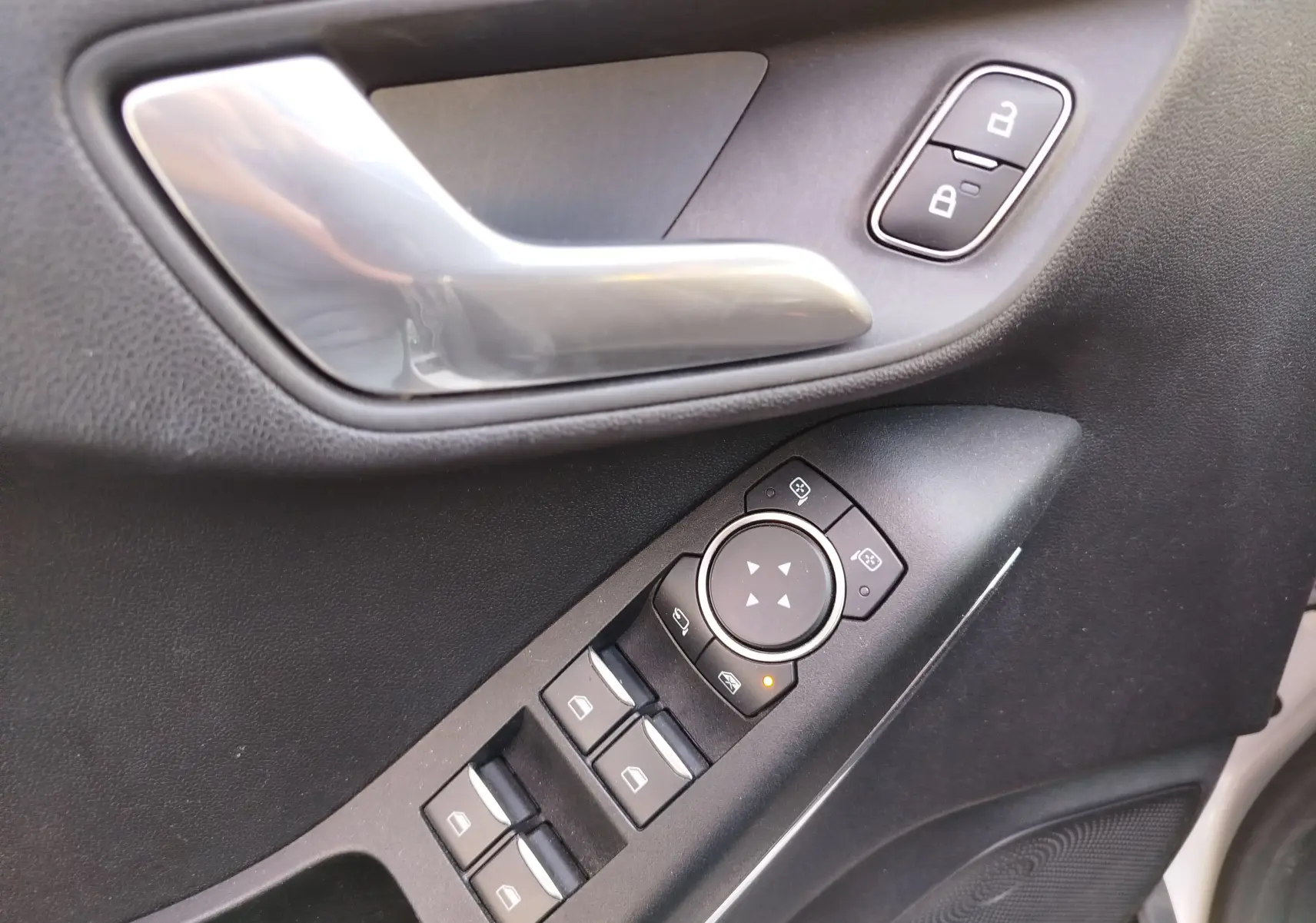 Gros plan sur la porte côté conducteur de la Ford Fiesta gris lunaire, avec commandes de vitres et poignée argentée.