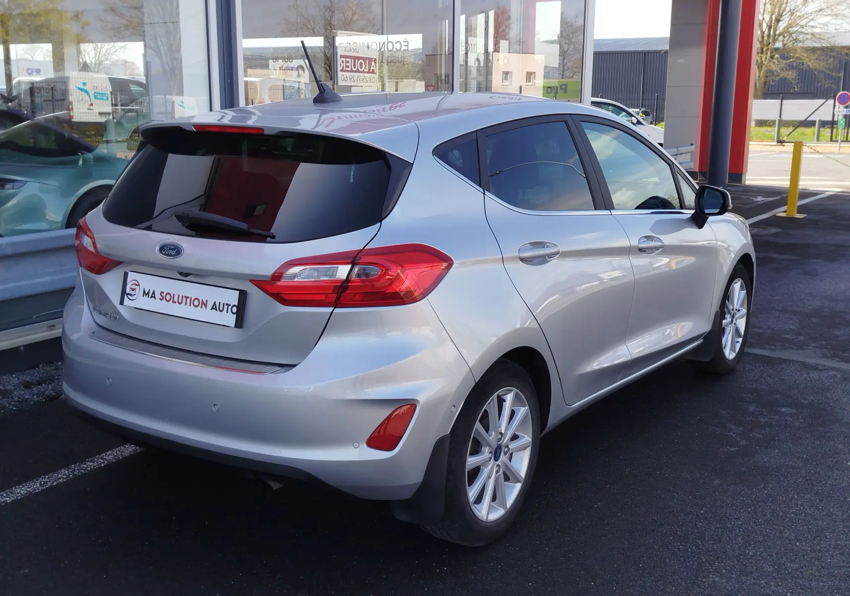 Vue 3/4 arrière droite d'une Ford Fiesta gris lunaire 2019 avec vitres teintées et feux arrière LED.