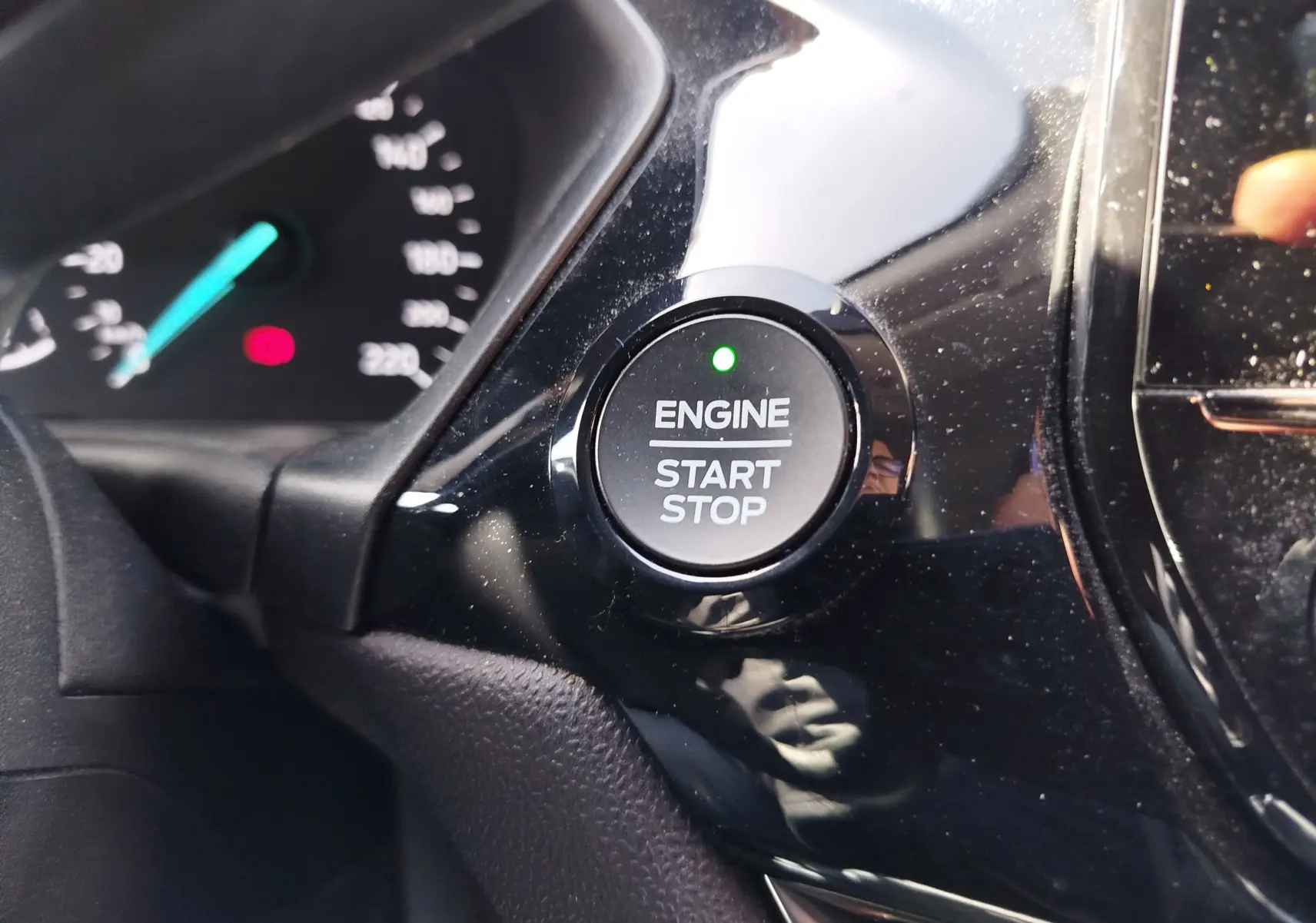 Gros plan sur le bouton moteur start/stop avec témoin vert, tableau de bord partiellement visible d'une Ford Fiesta gris lunaire.