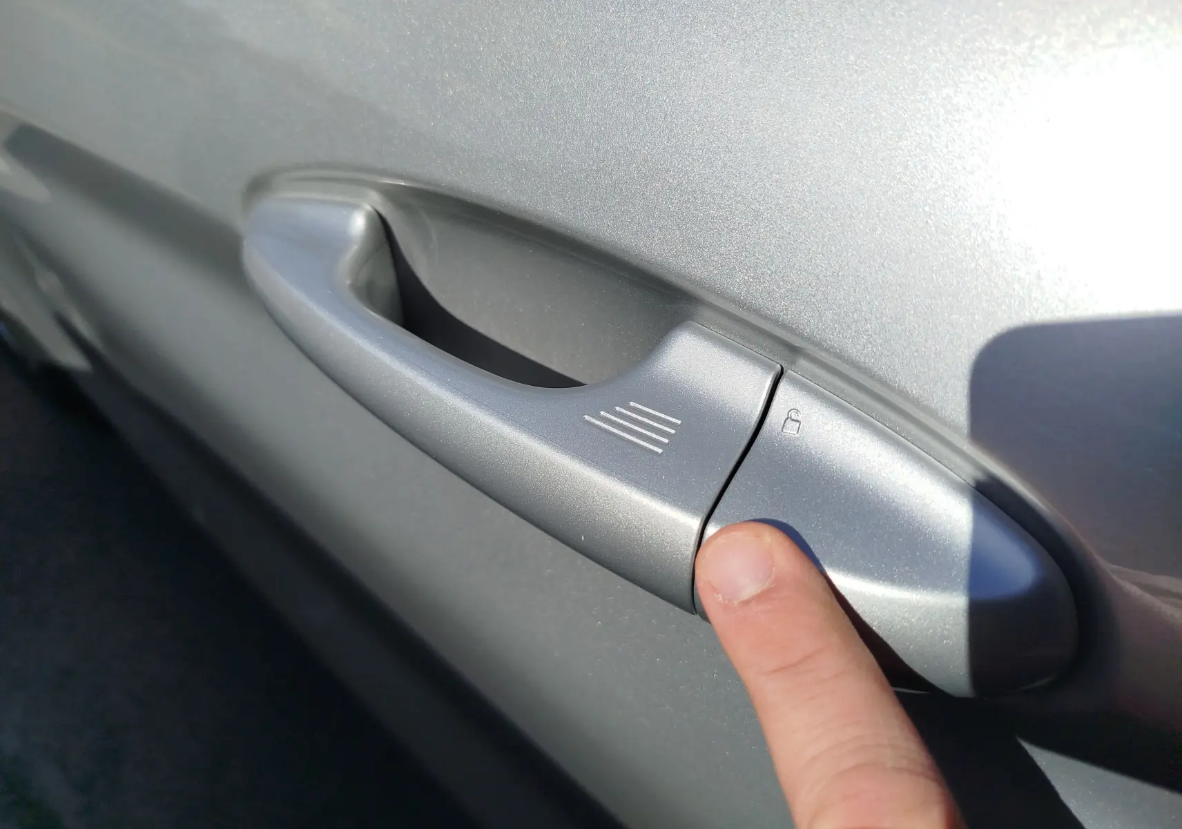 Gros plan sur la poignée de porte côté gauche gris lunaire d'une Ford Fiesta 2019 avec doigt appuyant sur le bouton de verrouillage.