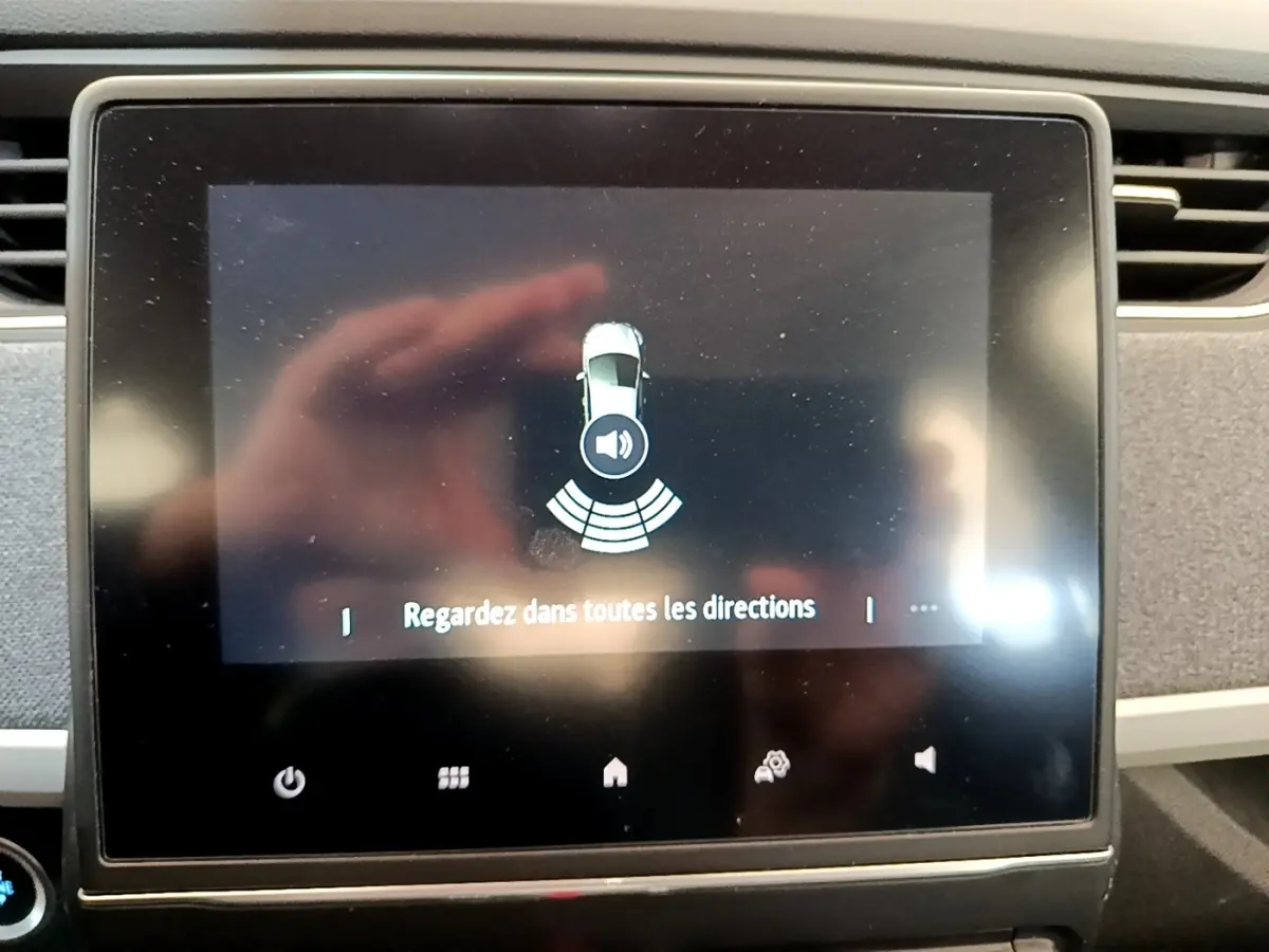 Écran tactile central de la Renault ZOE gris clair, affichant l'alerte de surveillance des angles morts.